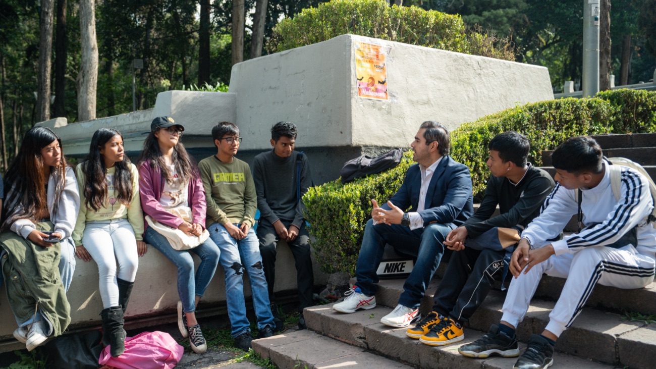 Lalo Del Mazo conversando sentado con jóvenes de la alcaldía